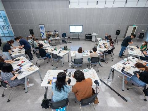 Students work together around shared tables in a modern classroom.