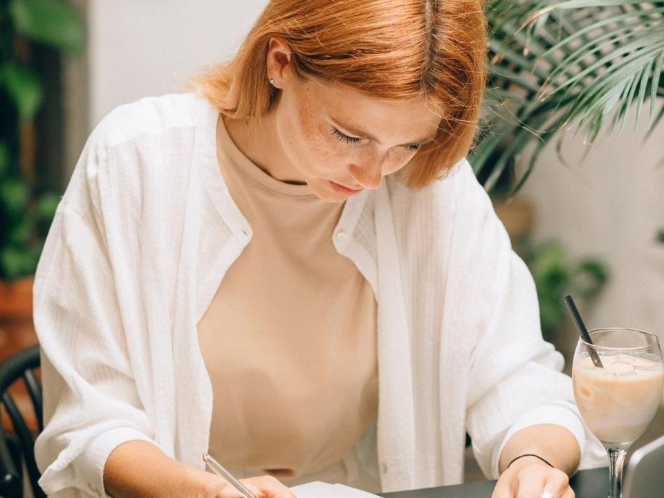 A woman reviews financial documents beside a laptop and calculator.